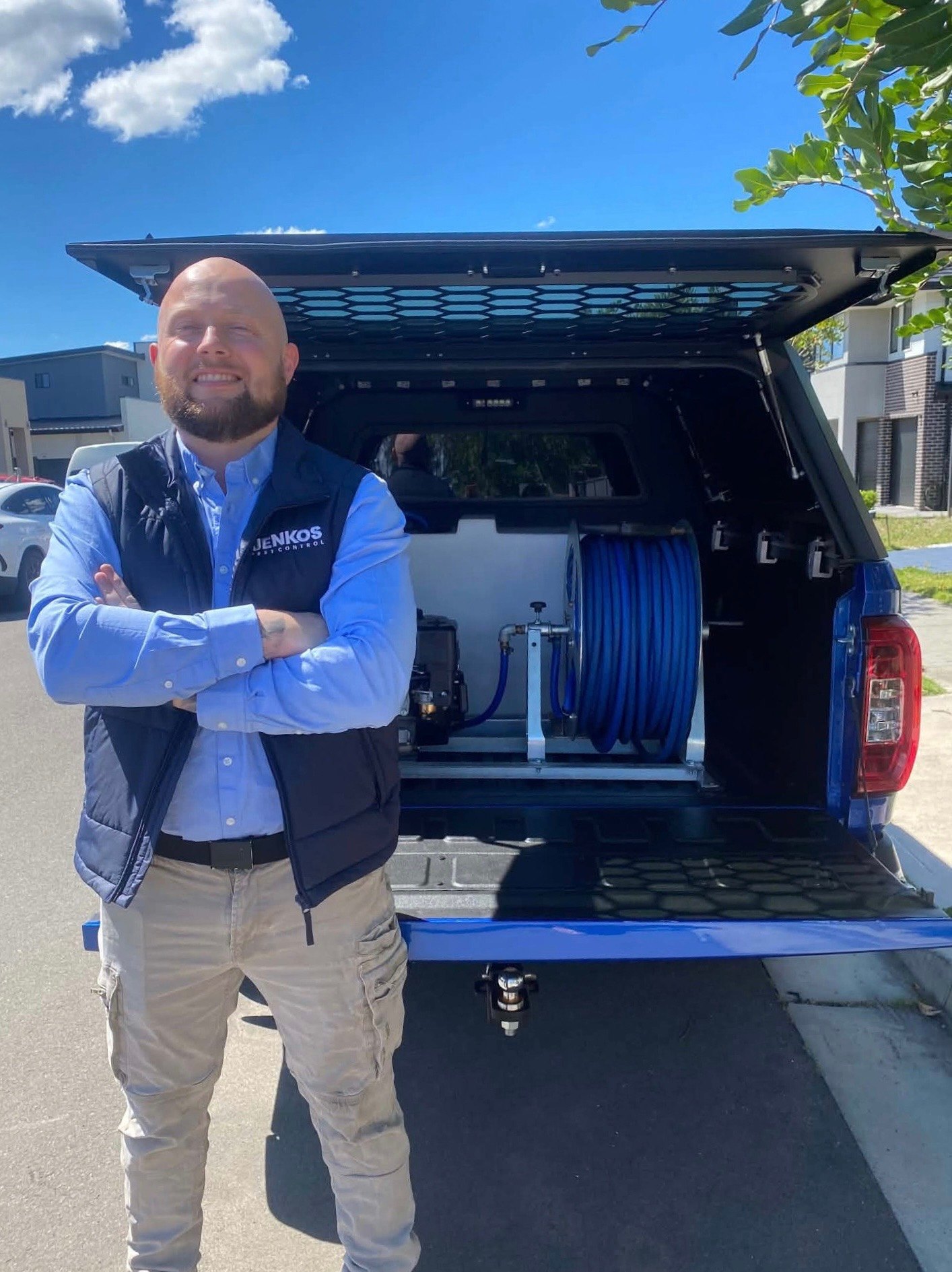 Blake from Jenkos Pest Control standing beside his fully equipped blue pest control ute in Sydney